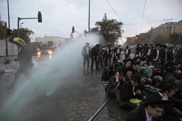 epa06352680 Police use a water canon to disperse Ultra-Orthodox Jewish demonstrators as they block the Jerusalem Light Rail during a protest against army recruitment in Jerusalem, Israel, 26 November  ...