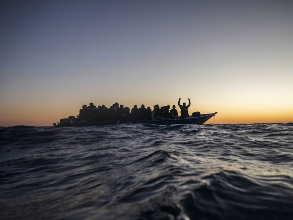 FILE - In this Friday, Feb. 12, 2021 file photo, migrants and refugees from different African nationalities wait for assistance on an overcrowded wooden boat, as aid workers of the Spanish NGO Open Ar ...