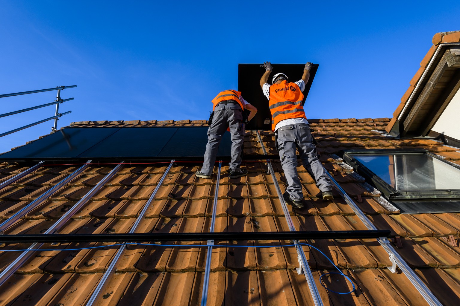 Deux installateurs du Groupe E installent un panneau solaire photovoltaique sur le toit d&#039;une habitation le mercredi 2 novembre 2022 a Fribourg. (KEYSTONE/Jean-Christophe Bott)