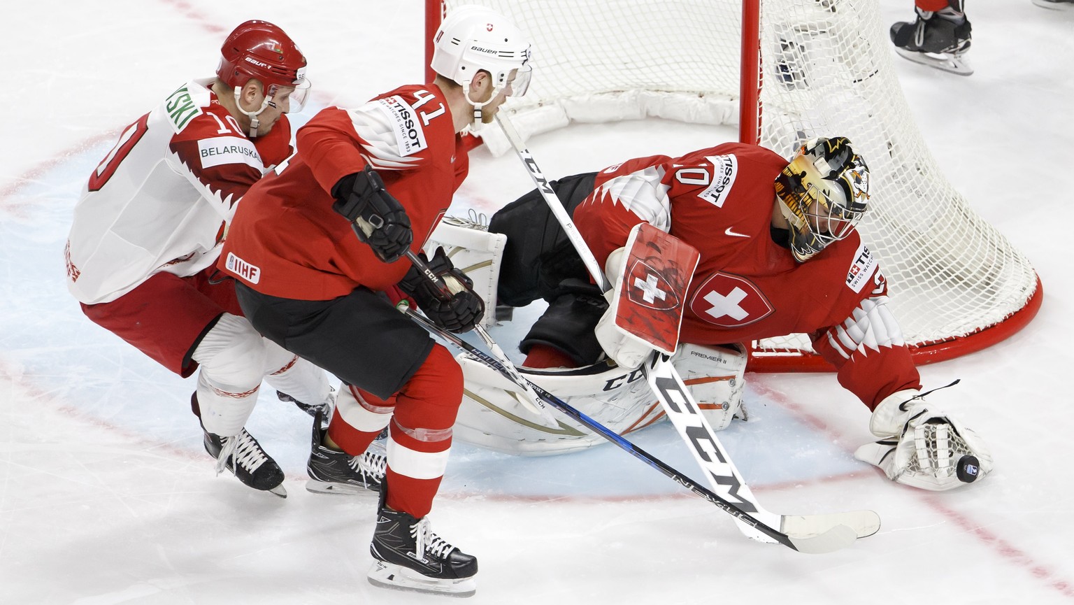 epa06722782 Switzerland&#039;s goalkeeper Reto Berra (R) in action with tBelarus&#039; forward Pavel Razvadovsky (L) and Switzerland&#039;s defender Mirco Mueller (C) during the IIHF 2018 World Champi ...