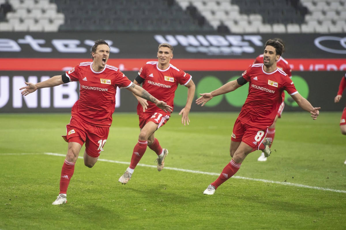 Union Berlin's Max Kruse, left, cheers with Union Berlin's Robin Knoche and Union Berlin's Rani Khedira after he scored the opening goal during the Bundesliga soccer match between Borus ...