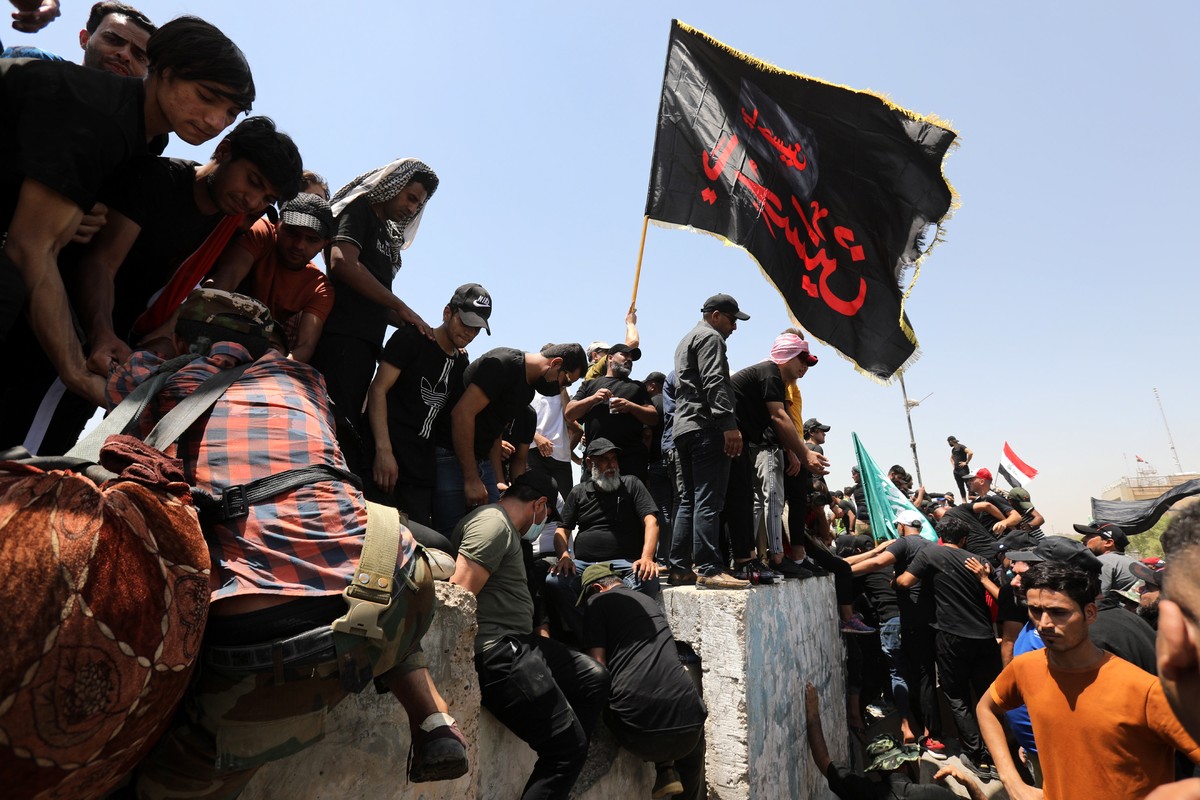 epa10098832 Supporters of Iraqi Shiite cleric Muqtada al-Sadr, head of the Sadrist movement, try to cross over the concrete blocks on the al-Jumhuriya bridge that leads to the 'Green Zone' i ...