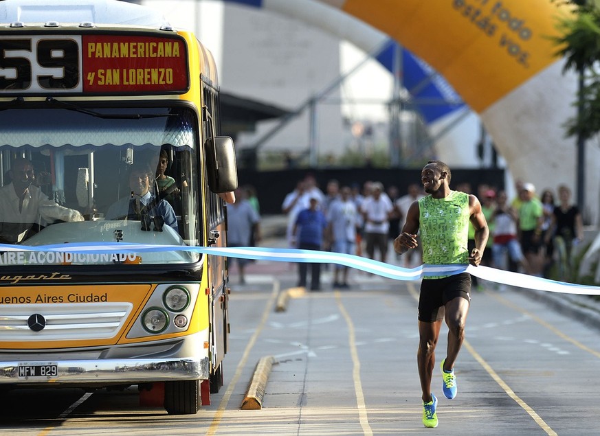 Olympic gold medalist Usain Bolt of Jamaica crosses the finish line to win a 100-meter exhibition against a bus along the 9 de Julio Avenue in Buenos Aires, Argentina, Saturday, Dec. 14, 2013. (AP Pho ...
