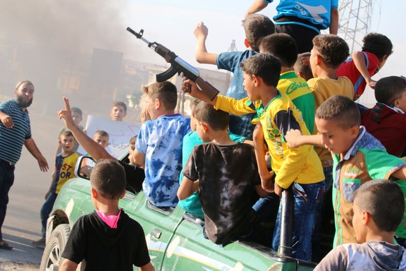 A boy carries a toy gun while riding a pick-up truck with other boys during a demonstration calling for aid to reach Aleppo near Castello road in Aleppo, Syria, September 14, 2016. REUTERS/Abdalrhman  ...