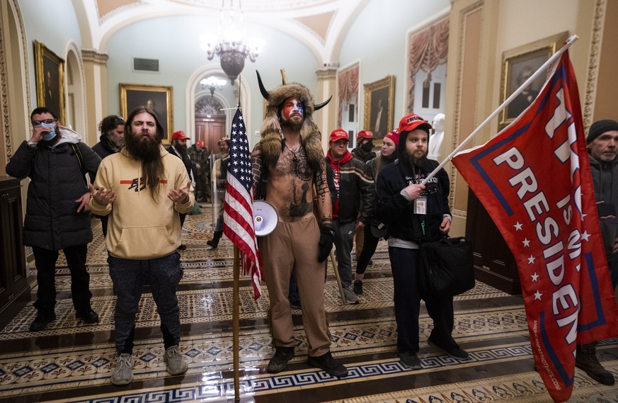 epa08976298 (FILE) - Supporters of US President Donald J. Trump, including &#039;QAnon Shaman&#039; Jacob Anthony Angeli Chansley (C), stand by the door to the Senate chambers after they breached the  ...
