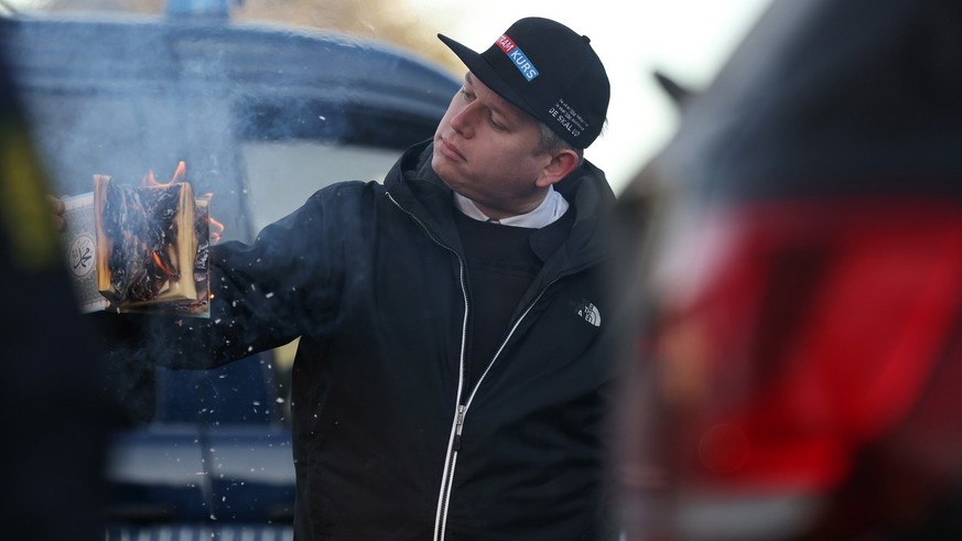 epa10433884 Rasmus Paludan, leader of Danish far-right anti-Islam party Stram Kurs (Hard Line), burns a copy of the Koran in front of the Turkish embassy in Copenhagen, Denmark, 27 January 2023. The a ...