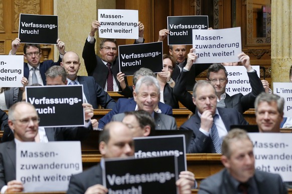 Nationalraete der SVP halten Plakate mit der Aufschrift &quot;Verfassungsbruch&quot; und &quot;Massenzuwanderung geht weiter&quot; hoch, bei der Schlussabstimmung ueber die Masseneinwanderungsinitiati ...