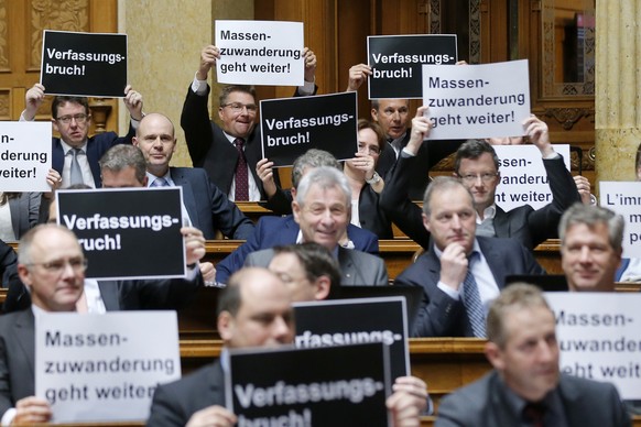 Nationalraete der SVP halten Plakate mit der Aufschrift &quot;Verfassungsbruch&quot; und &quot;Massenzuwanderung geht weiter&quot; hoch, bei der Schlussabstimmung ueber die Masseneinwanderungsinitiati ...