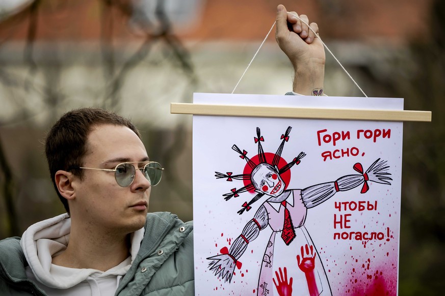 epa11225776 A person holds a placard as Russians wait in line to vote at the Russian embassy in The Hague, Netherlands, 17 March 2024. Russia presidential elections vote takes place between 15 and 17  ...