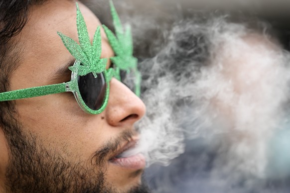 A man smoking cannabis in front of the Cathedral in Cologne, Germany, on a public consumption event at the start of a new law on Monday, April 1, 2024. Germany has legalized the possession of small am ...