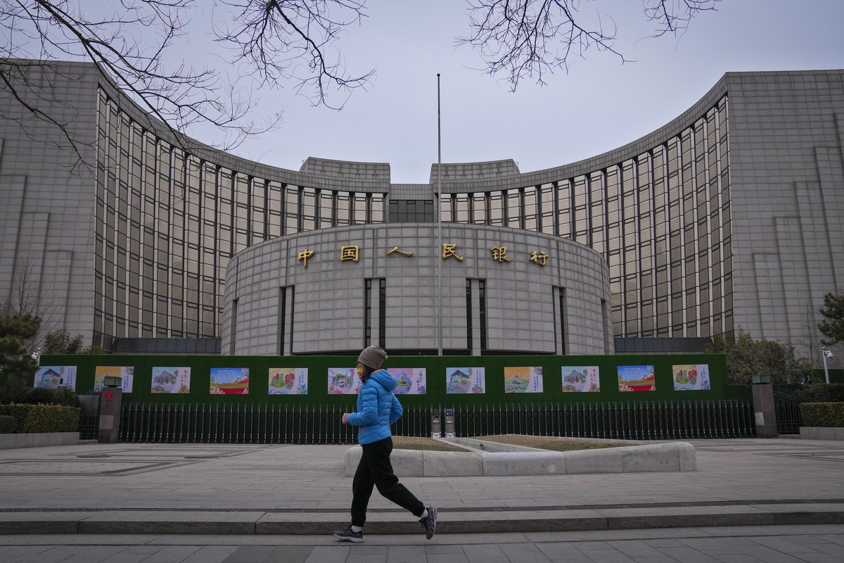 A woman jogs past China's central bank, or the People's Bank of China in Beijing, Tuesday, Feb. 20, 2024. China's central bank announced it cut its five-year loan prime rate while leavi ...