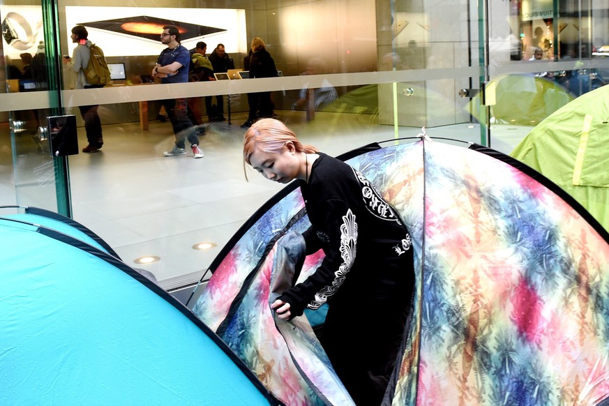 epa04946200 A customer returns to her place in the queue outside of the Apple Store in Sydney, Australia, 24 September 2015, to be the first in queue for the new iPhones. Apple will release the iPhone ...