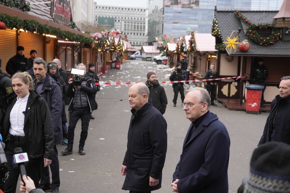 The Chancellor of Germany Olaf Scholz, center, leaves after placing flowers outside St. John&#039;s Church near a Christmas Market, where a car drove into a crowd on Friday evening, in Magdeburg, Germ ...