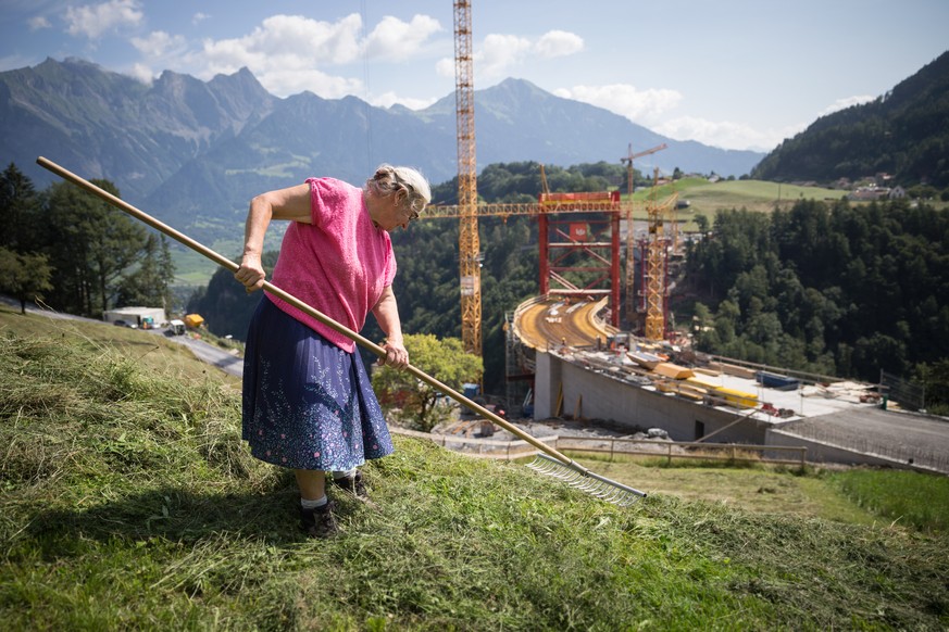 Eine Baeuerin beim Heuen vor der Taminabruecke bei Valens im st. gallischen Taminatal am Mittwoch, 6. August 2015. Die Bauarbeiten an der groesste Bogenbruecke der Schweiz schreiten planmaessig voran  ...