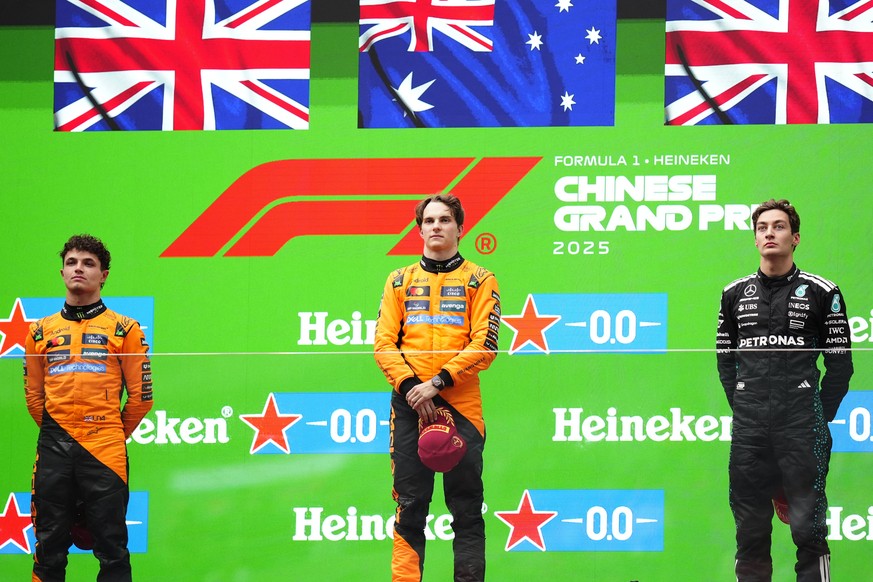 McLaren driver Oscar Piastri of Australia, centre, is flanked on the podium with McLaren driver Lando Norris of Britain, left, and Mercedes driver George Russell of Britain after winning the Chinese F ...