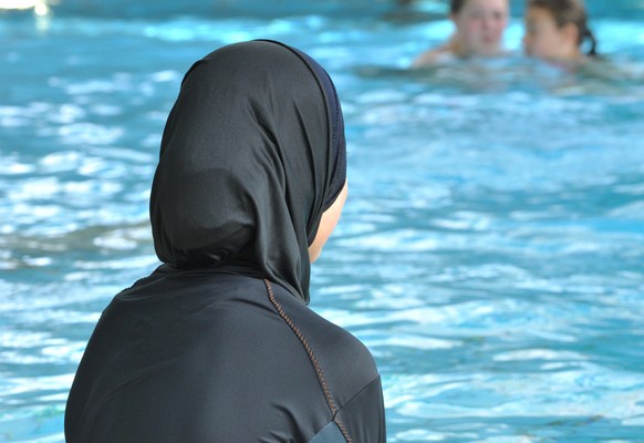 ARCHIV - Eine muslimische Schülerin sitzt am 23.06.2009 in einem Ganzkörper-Badeanzug (Burkini) am Rande eines Schwimmbeckens. Zwei muslimische Eltern aus Basel wehren sich vor dem Europäischen Mensch ...