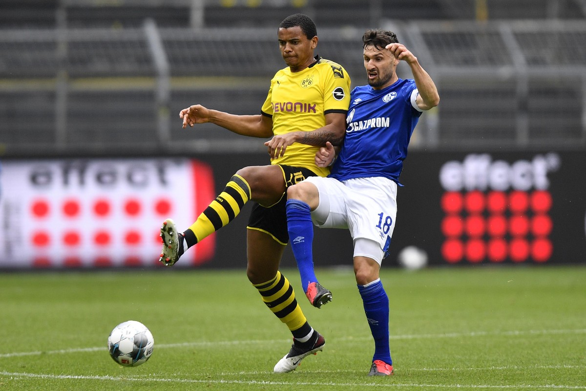 epa08425905 Dortmund's Manuel Akanji (L) vies for the ball with Schalke's Daniel Caligiuri during the German Bundesliga soccer match between Borussia Dortmund and Schalke 04 in Dortmund, Ger ...