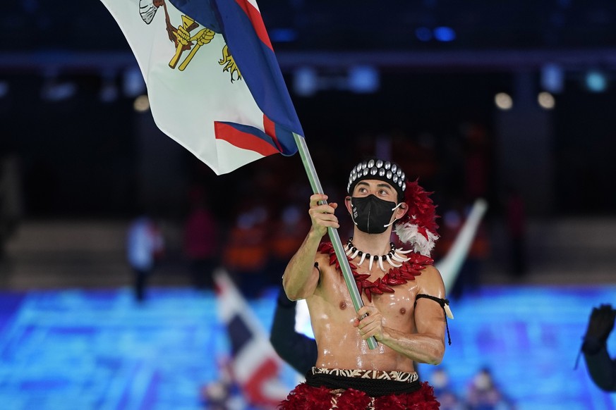 Nathan Crumpton, of American Samoa, carries his national flag into the stadium during the opening ceremony of the 2022 Winter Olympics, Friday, Feb. 4, 2022, in Beijing. (AP Photo/Jae C. Hong)