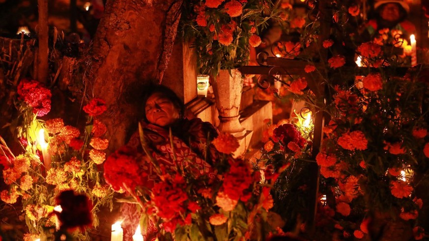 ATZOMPA, MEXICO - NOVEMBER 01: A woman rests at the tomb of her relative during &#039;Day of the Dead&#039; celebrations on the graveyard of Atzompa on November 01, 2022 in Atzompa, Mexico. Considered ...