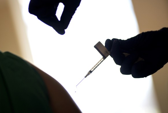 FILE - A droplet falls from a syringe after a health care worker was injected with the Pfizer-BioNTech COVID-19 vaccine at a hospital in Providence, R.I., Tuesday, Dec. 15, 2020. In 2023, many conspir ...