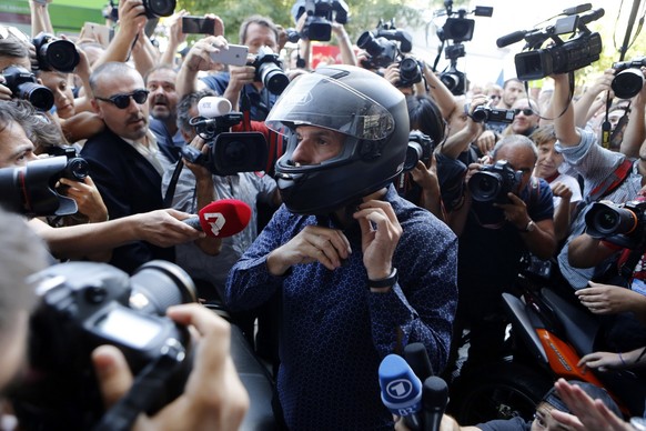 Outgoing Greek Finance Minister Yanis Varoufakis puts his helmet on as he is surrounded by media after his resignation in Athens, Monday, July 6, 2015. Greece and its membership in Europe&#039;s joint ...