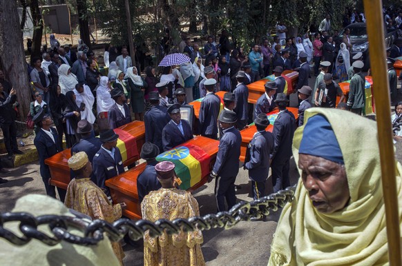 Relatives grieve next to empty caskets draped with the national flag at a mass funeral at the Holy Trinity Cathedral in Addis Ababa, Ethiopia Sunday, March 17, 2019. Thousands of Ethiopians have turne ...