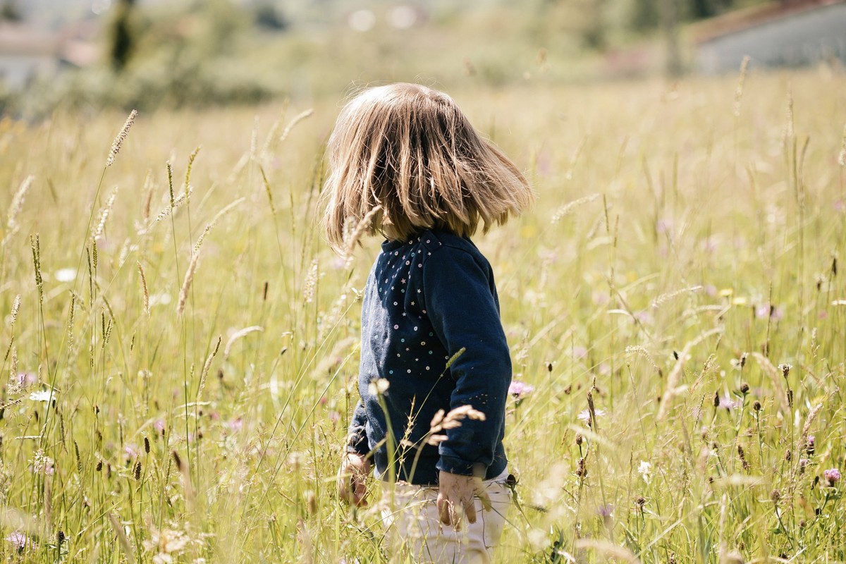 Front view of a blonde girl looking backwards in a field of flowers. Concept of nature.