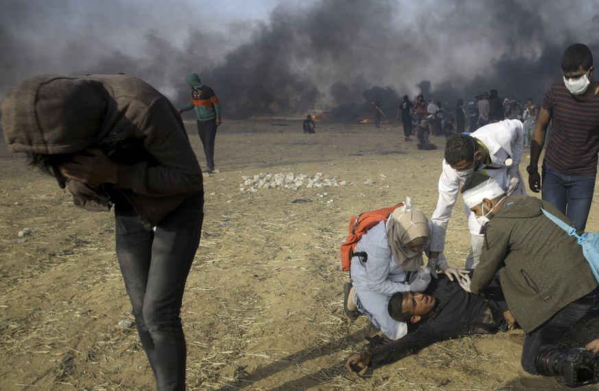 Palestinian medics treat a protester suffering from teargas fired by Israeli troops during a protest at the Gaza Strip&#039;s border with Israel, east of Khan Younis, Tuesday, May 15, 2018. Israel fac ...