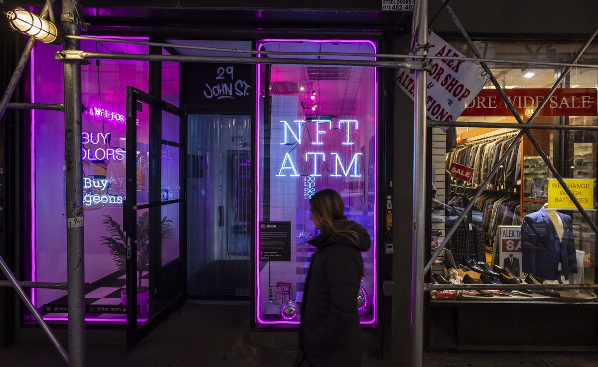 epa09799794 People walk past an NFT (non-fungible token) ATM in a small storefront in the Financial District of New York, New York, USA, 03 March 2022. The NFT ATM, which is billed as the world?s firs ...