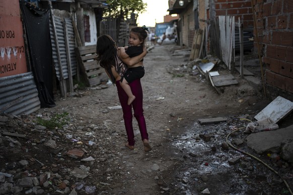 A girl carries a baby in Puerta 8, a low income neighborhood north of Buenos Aires, Argentina, Wednesday, Feb. 9, 2022, where contaminated cocaine may have been sold. A batch of that toxic cocaine has ...