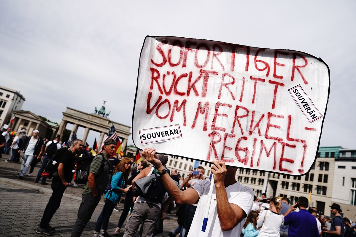 29.08.2020, Berlin: Ein Teilnehmer mit dem Plakat "Sofortiger R�cktritt vom Merkel-Regime!" steht vor einer Demonstration gegen die Corona-Ma�nahmen am Brandcenburger Tor. Foto: Kay Nietfeld ...
