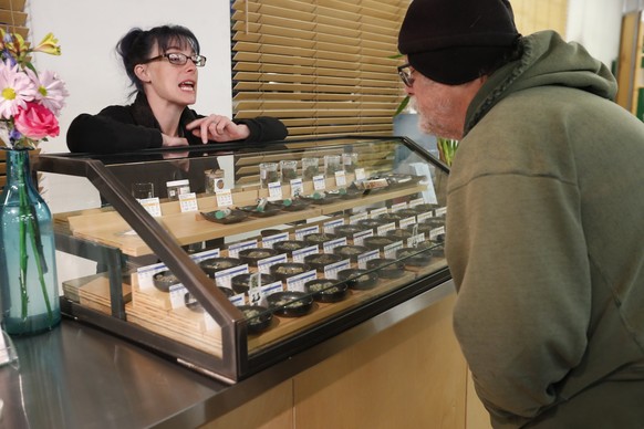 epa06412913 A sales clerk helps a customer with cannabis samples on display at the Harborside cannabis dispensary in Oakland, California, USA, 01 January 2018. In November 2016, California voters lega ...