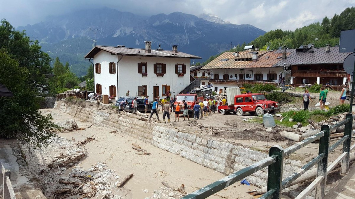 epa06126325 A handout image made available by the Alpine and Speleological Rescue of Veneto region shows local residents inspecting the damages caused by flooding of the Bigontina stream near Cortina  ...
