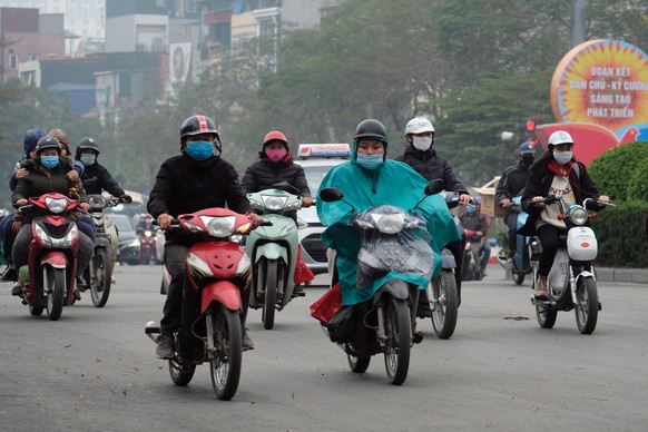 epa08970256 People wearing face masks ride motorbikes on a street in Hanoi, Vietnam, 28 January 2021. Vietnam reported its first two cases of COVID-19 disease community transmission in nearly two mont ...