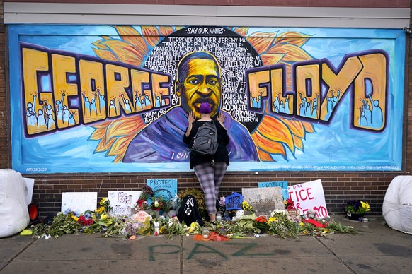 FILE - In this Friday, April 23, 2021 file photo, Damarra Atkins pays respect to George Floyd at a mural at George Floyd Square in Minneapolis. Newly released video that shows Minneapolis police offic ...