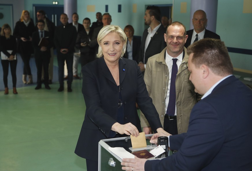 CORRECTS NAME OF THE MAN - Far-right leader and candidate for the 2017 French presidential election Marine Le Pen casts her vote for the first-round presidential election while National Front Henin-Be ...