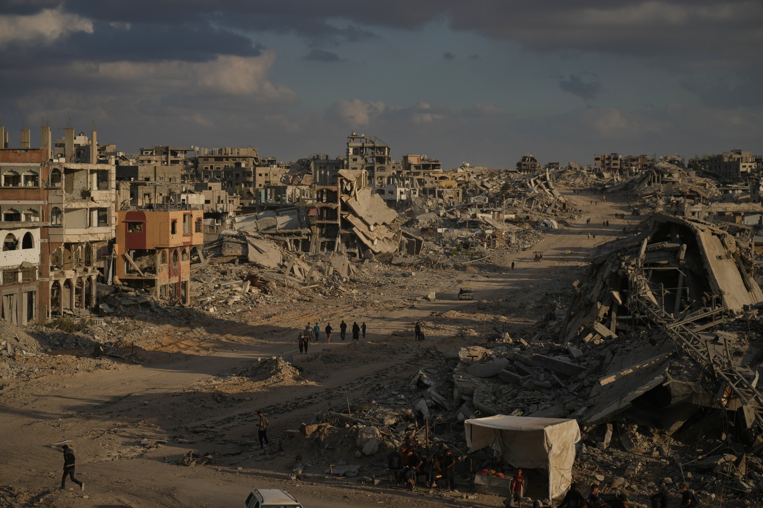 Palestinians walk among destroyed buildings in Gaza City, Sunday, Oct. 12, 2025, after Israel and Hamas agreed to a pause in their war and the release of the remaining hostages. (AP Photo/Jehad Alshra ...