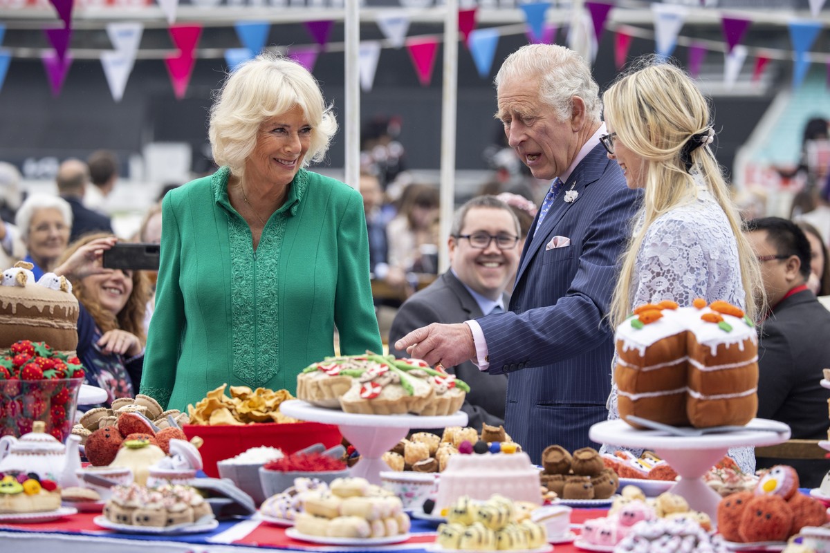 epa09997068 Britain's Prince Charles, the Prince of Wales (R) and Camilla Duchess of Cornwall (C) look at hand-sewn street party decorations as they attend The Big Lunch at the Oval Kennington to ...