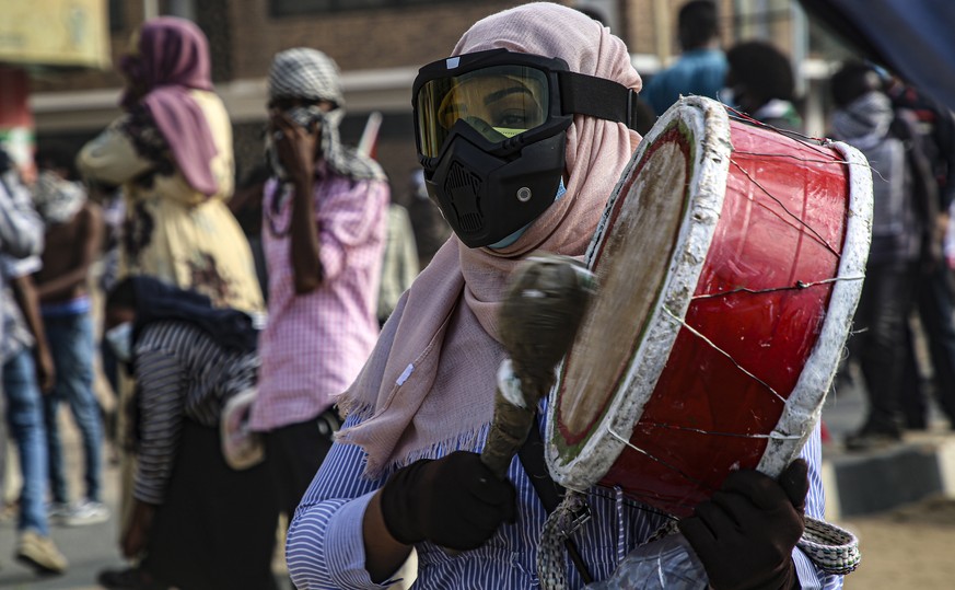 epa09656653 A female Sudanese protester plays drum as they clash with security forces during an anti-coup protest near the presidential palace in the capital Khartoum, Sudan, 25 December 2021. Thousan ...