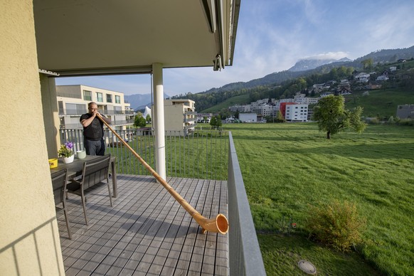 Der Alphornblaeser David Reimann von der Alphornvereinigung Kriens-Pilatus blaest um 19:00 Uhr wie viele andere Alphornblaeser in der Schweiz zum Dank fuer alle im Einsatz stehenden Menschen im Kampf  ...