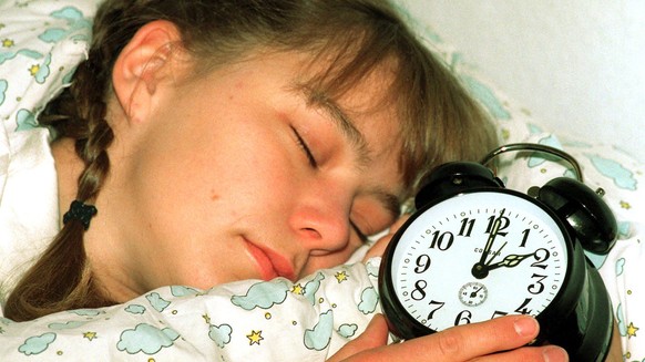 ** ARCHIV ** Illustration zum Thema Sommerzeit: Mit der Uhr im Griff liegt die Berlinerin Maren am 26. Maerz 2000 im Bett. In der Nacht zu Sonntag, 30. Maerz 2003, werden in Deutschland zum Beginn der ...