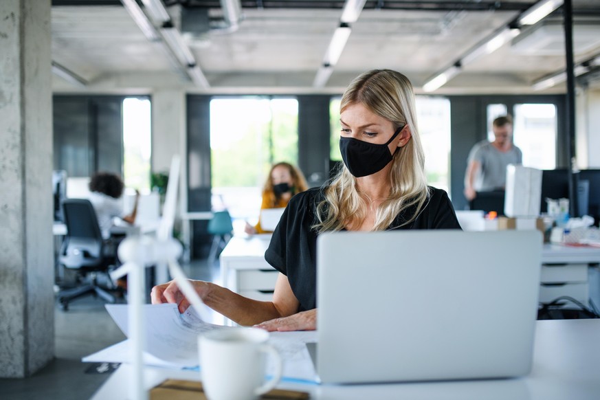 Frau mit Maske am Arbeitsplatz