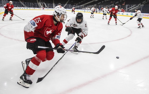 Switzerland&#039;s Jonas Taibel (25) and Austria&#039;s David Reinbacher (5) work for the puck during the second period of an IIHF world junior hockey championships game Monday, Aug. 15, 2022, in Edmo ...