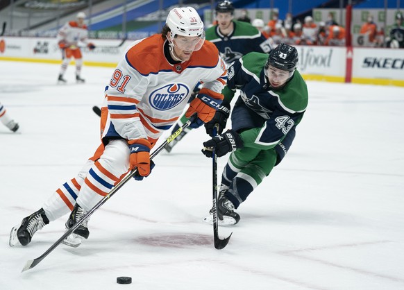 Edmonton Oilers center Gaetan Haas (91) tries to keep the puck from Vancouver Canucks defenseman Quinn Hughes (43) during the third period of an NHL hockey game Tuesday, Feb. 23, 2021, in Vancouver, B ...