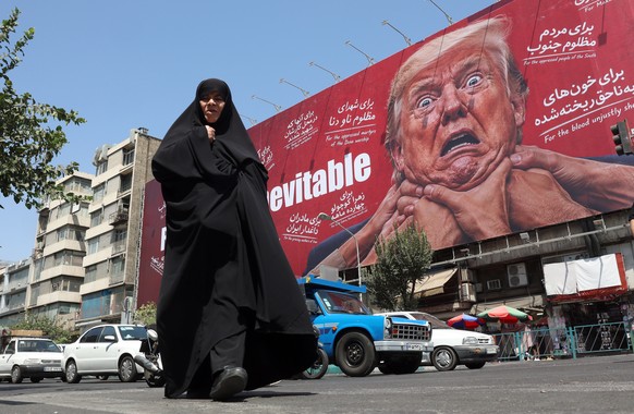 KEYPIX - epa13178254 A woman walks next to an anti-Trump billboard in Tehran, Iran, 19 August 2026. Iranian parliament speaker Mohammad Bagher Ghalibaf said that the Strait of Hormuz will remain close ...
