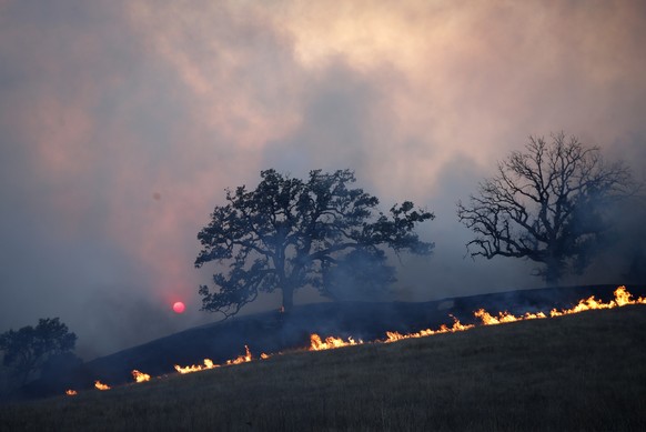 epa07154614 The sun sets a fire burns in Malibu State Park as the the Woolsey Fire sweeps through Malibu, California, USA, 09 November 2018. Wildfires in California have destroyed 150 homes and burned ...