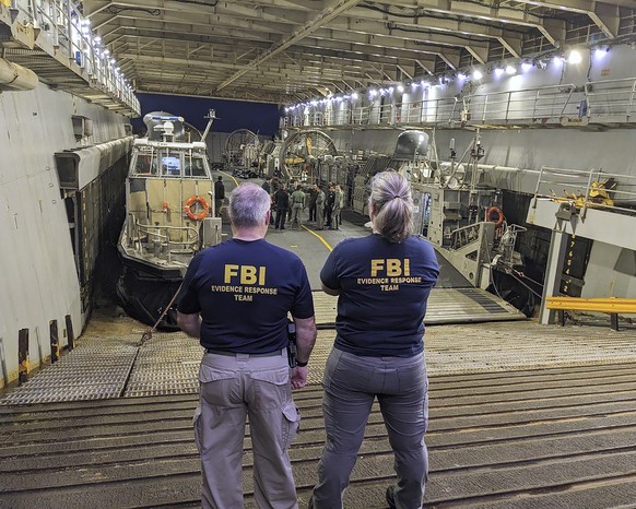 In this image provided by the FBI, members of the FBI's Evidence Team watch the high-altitude recovery operations of the downed balloon on a Department of Defense ship off the coast of Myrt...