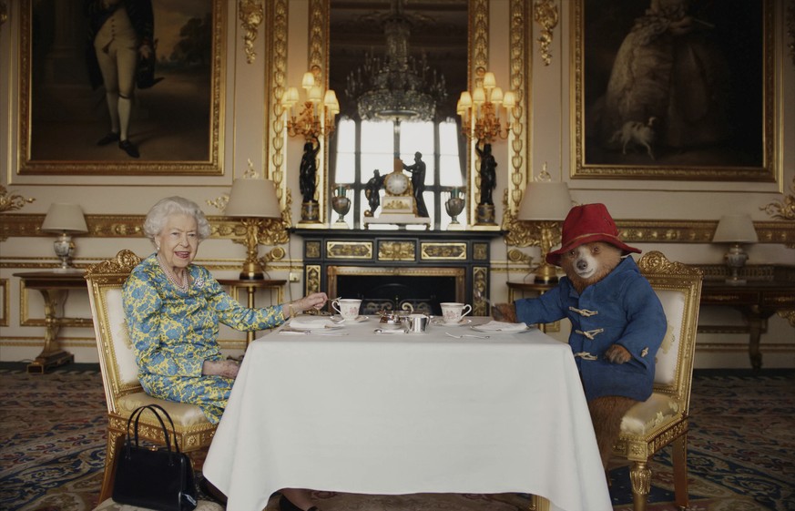 In this undated photo provided by Buckingham Palace/ Studio Canal / BBC Studios / Heyday Films on Saturday, June 4, 2022, Britain&#039;s Queen Elizabeth II and Paddington Bear have cream tea at Buckin ...