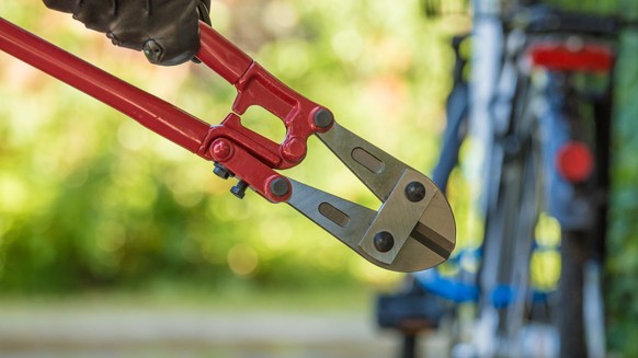 Ein Dieb macht sich auf den Weg, um ein Velo mit seinem Bolzenschneider zu stehlen.