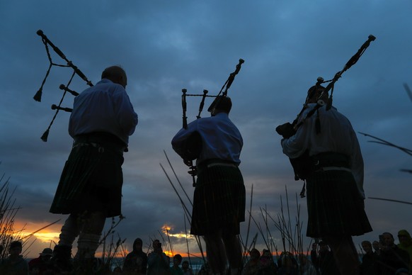 epa06411620 Men play bag-pipes during new years eve celebrations at sunset on Scarborough beach in Cape Town, South Africa, 31 December 2017. The local tradition sees the pipers playing out the year t ...